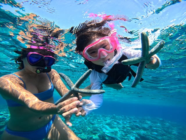 沖縄の海でシュノーケリング中に見つけたヒトデと一緒に記念写真