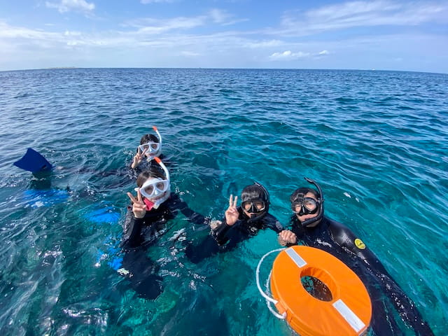 沖縄の海でシュノーケリングを楽しんでる家族写真