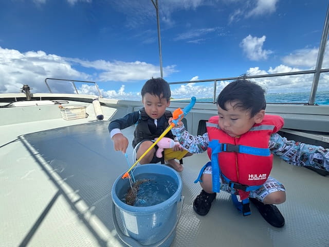 沖縄の海でシュノーケリング体験中の子どもたちが船上で海の生き物を観察している様子
