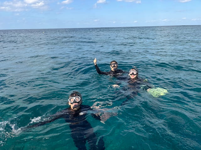 学生グループで沖縄の海をシュノーケリングで楽しんでる写真